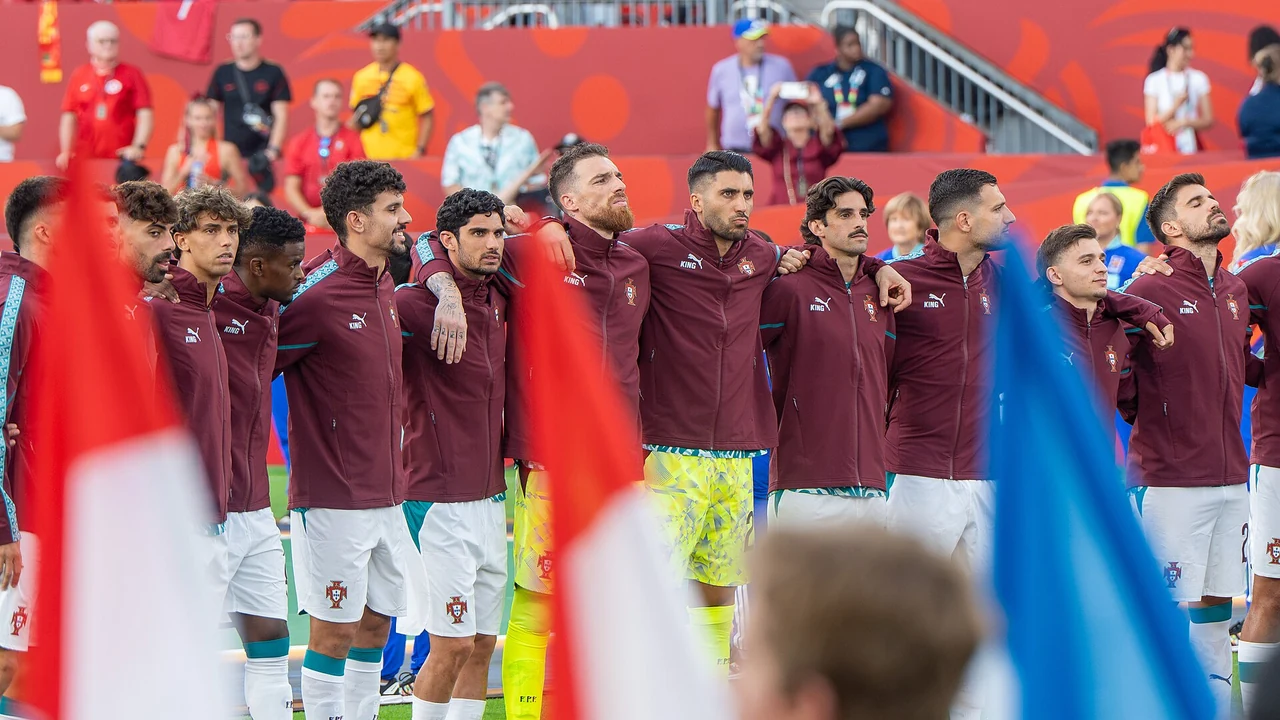 Jogadores da Seleção perfilados para o hino, com bandeiras portuguesas e o estádio cheio ao fundo